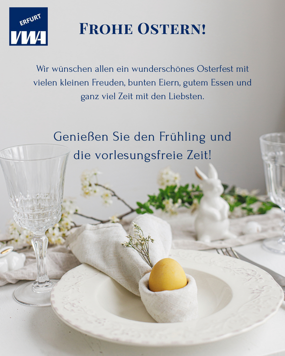 Ein Ostertisch mit einem dekorativen Teller, darauf ein gelbes Ei, umgeben von einer Serviette und frischen Blumen. Im Hintergrund stehen ein Weinglas und eine kleine Hasenfigur. Der Text wünscht frohe Ostern und eine schöne Frühlingszeit.