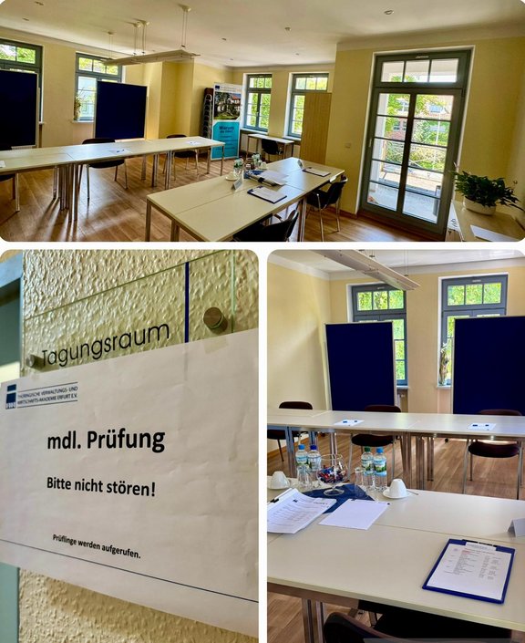 Ein Tagungsraum mit mehreren weißen Tischen und Stühlen. An der Wand hängt ein Schild mit der Aufschrift „mdl. Prüfung – Bitte nicht stören!“. Auf den Tischen sind Wasserflaschen, Tassen und Unterlagen verteilt. Fenster bieten Tageslicht und Blick ins Freie.